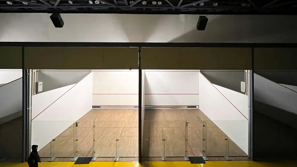Empty indoor squash court with a white front wall